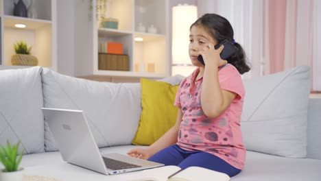 Girl-child-using-laptop-nervously-talking-on-the-phone.